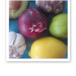 Närbild på en bit rödlök, gul citron, grön lime, vit vitlök, avokado och jordärtskocka.