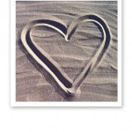 Ett hjärta ritat i sanden på en sandstrand.
